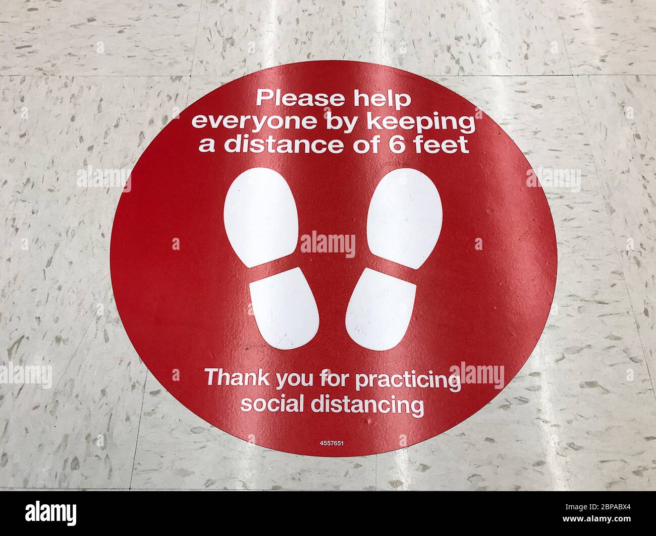 Cartello di divaricamento sociale sul pavimento del supermercato che chiede ai clienti di praticare una distanza di almeno 6 piedi per prevenire la diffusione del coronavirus Foto Stock