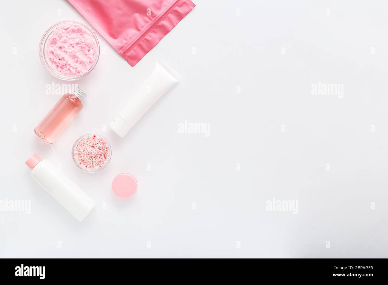 Set di prodotti rosa bianco per bagno di cura della pelle. Bottiglie cosmetiche, provette, confezionamento in crema, polvere e perle per vasche da bagno. Centro benessere cosmetico Foto Stock