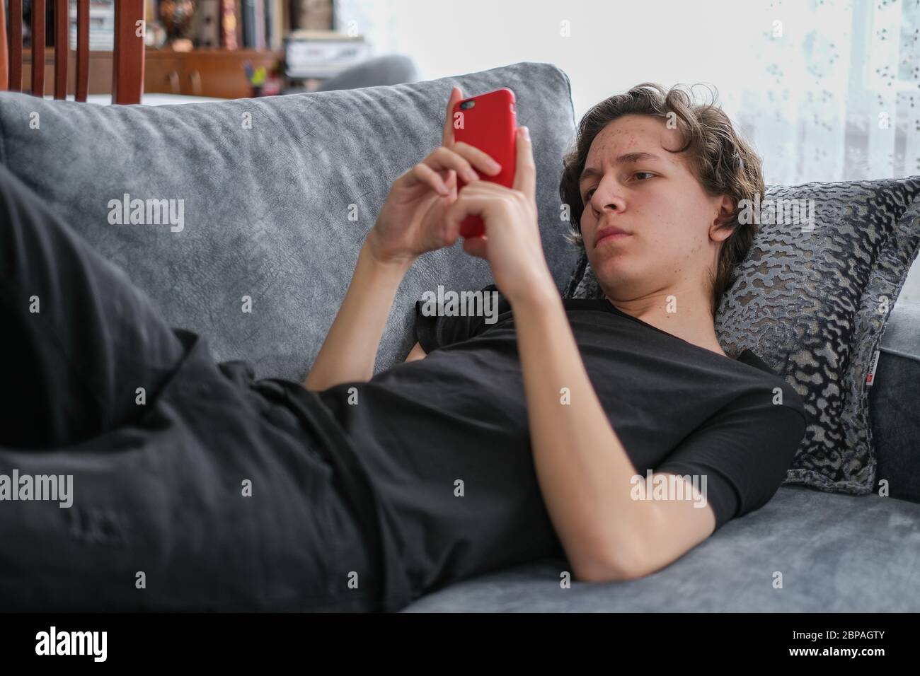 L'adolescente caucasico sta imparando da sul telefono mobile a casa nei giorni della corona. Foto Stock