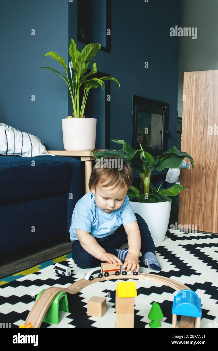 Un ragazzo carino sta giocando sul pavimento con le automobili. Il concetto di giochi per bambini, intrattenimento in quarantena, soggiorno a casa. Foto Stock