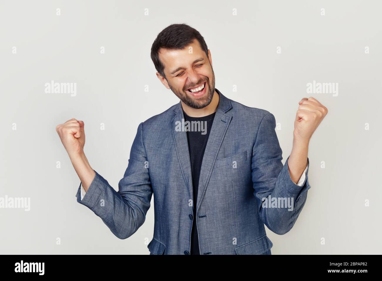 Ritratto di un giovane imprenditore energico che gode di successo. Il giovane uomo d'affari celebra il successo aziendale con le mani in su. Concetto vincitore. Foto Stock