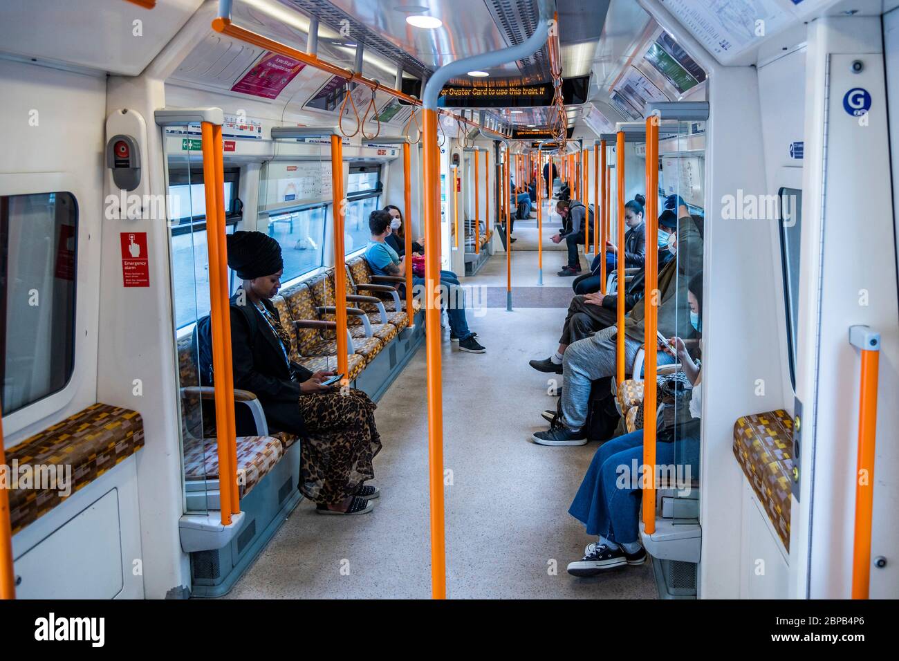 Londra, Regno Unito. 18 maggio 2020. Il terreno ha alcuni passengers con abbondanza di spazio per la distanza sociale, poche maschere di usura - sistemi di senso unico e personale supplementare per guidare la spola, ma i treni sono in gran parte vuoti, anche alle ore di punta. Il "blocco" dei morti continua per l'epidemia di Coronavirus (Covid 19) a Londra. Credit: Guy Bell/Alamy Live News Foto Stock