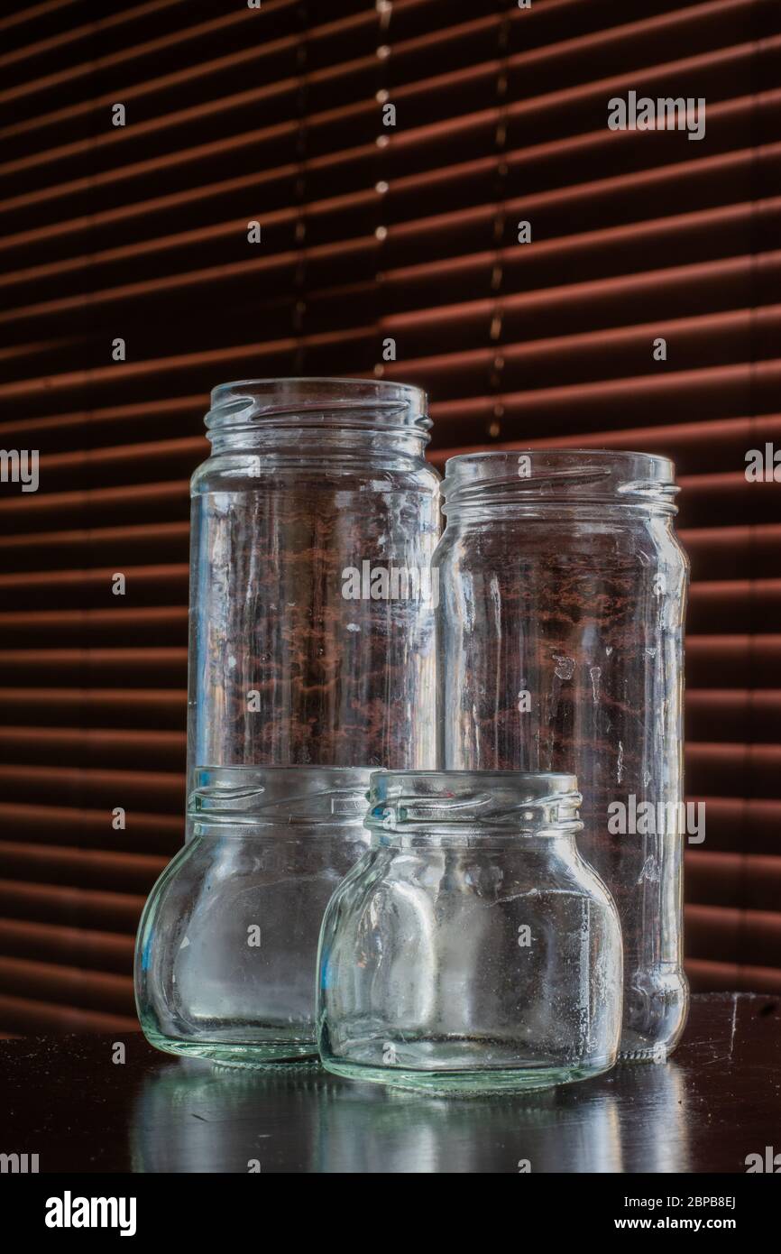 Quattro vasetti di vetro vuoti, usati e leggermente sporchi. Foto Stock