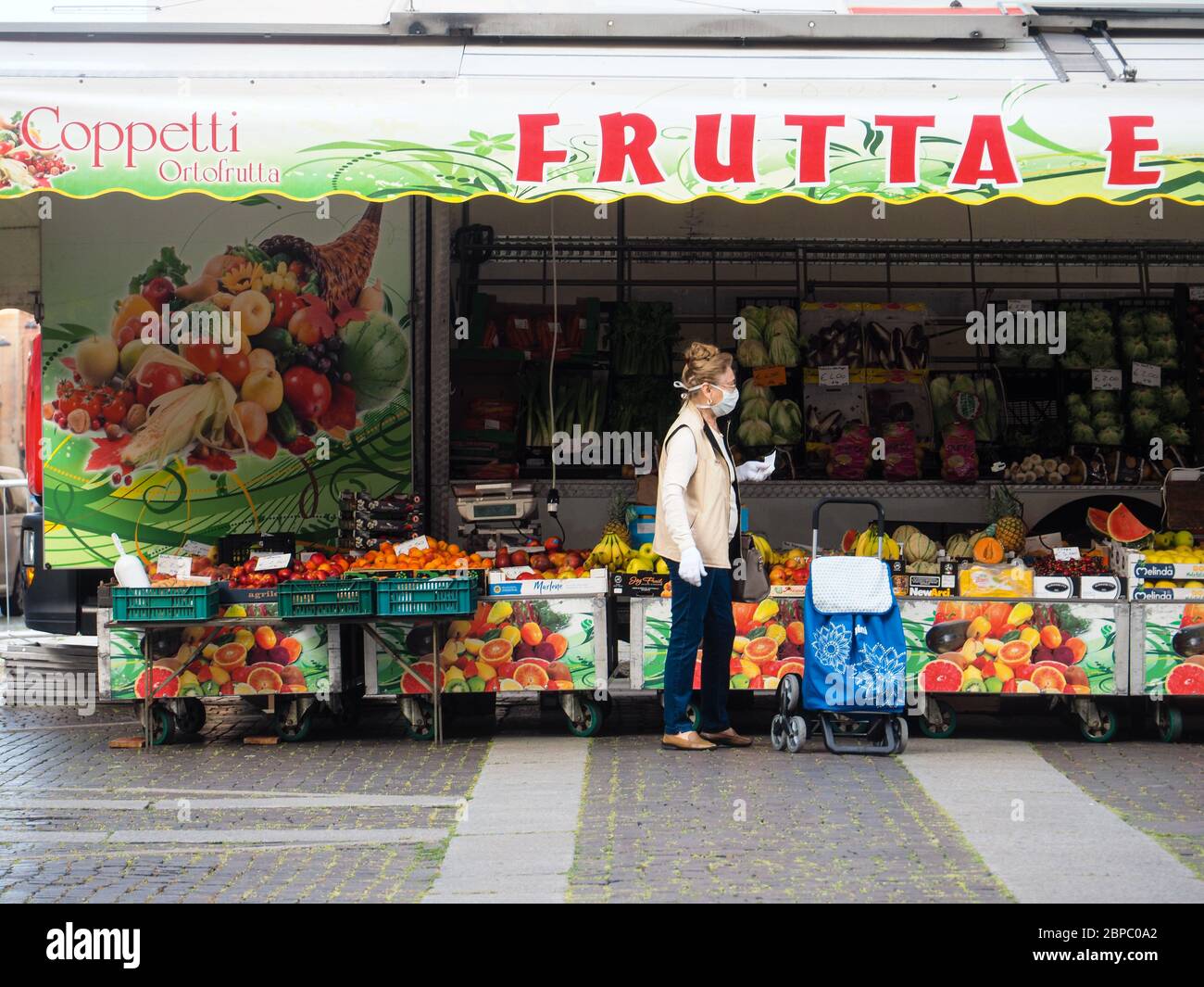 Cremona, Lombardia, Italia - 16 maggio 2020 - la gente acquista socialmente la distanza d nel mercato biologico locale dell'alimento all'aperto che indossa la maschera facciale Foto Stock