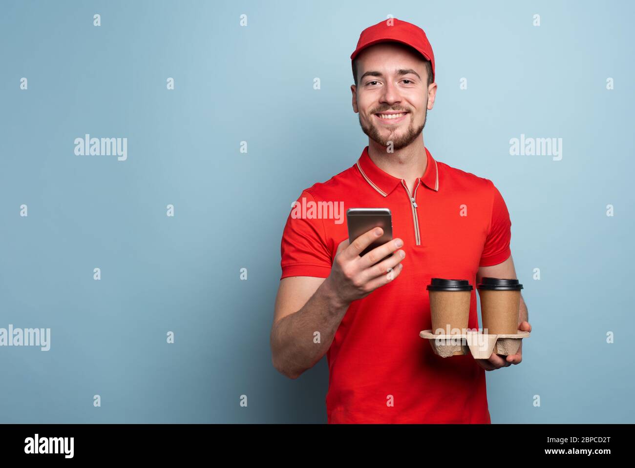 Il corriere è felice di consegnare caffè e cibo caldi. Sfondo ciano Foto Stock