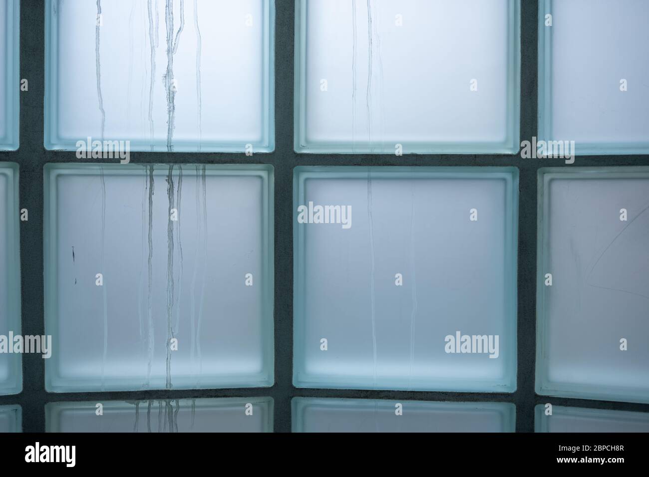 Interno dell'edificio che guarda ad una finestra opaca costruita con blocchi di vetro Foto Stock