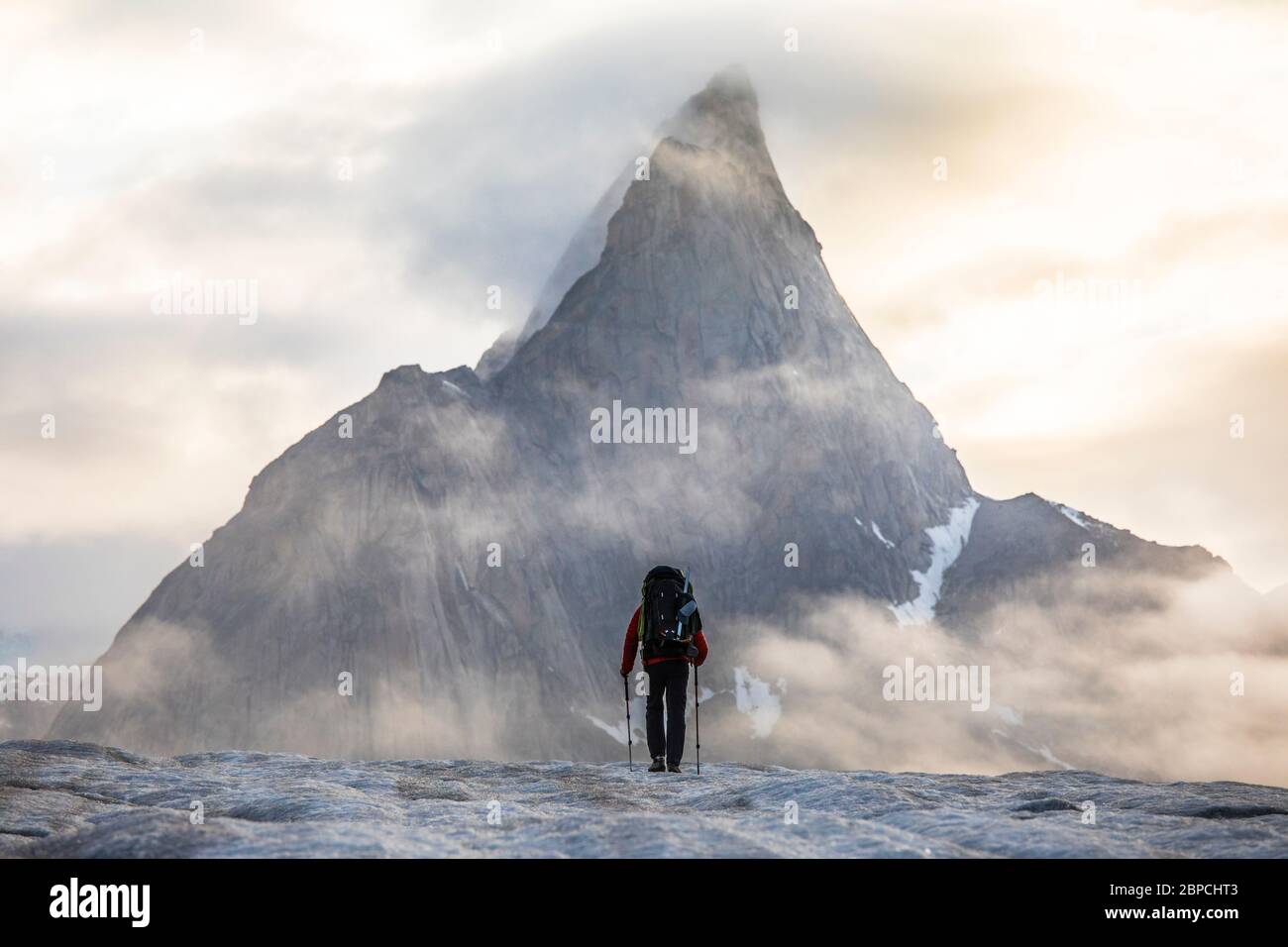 Vista posteriore dello zaino in spalla che si avvicina montagna drammatica. Foto Stock