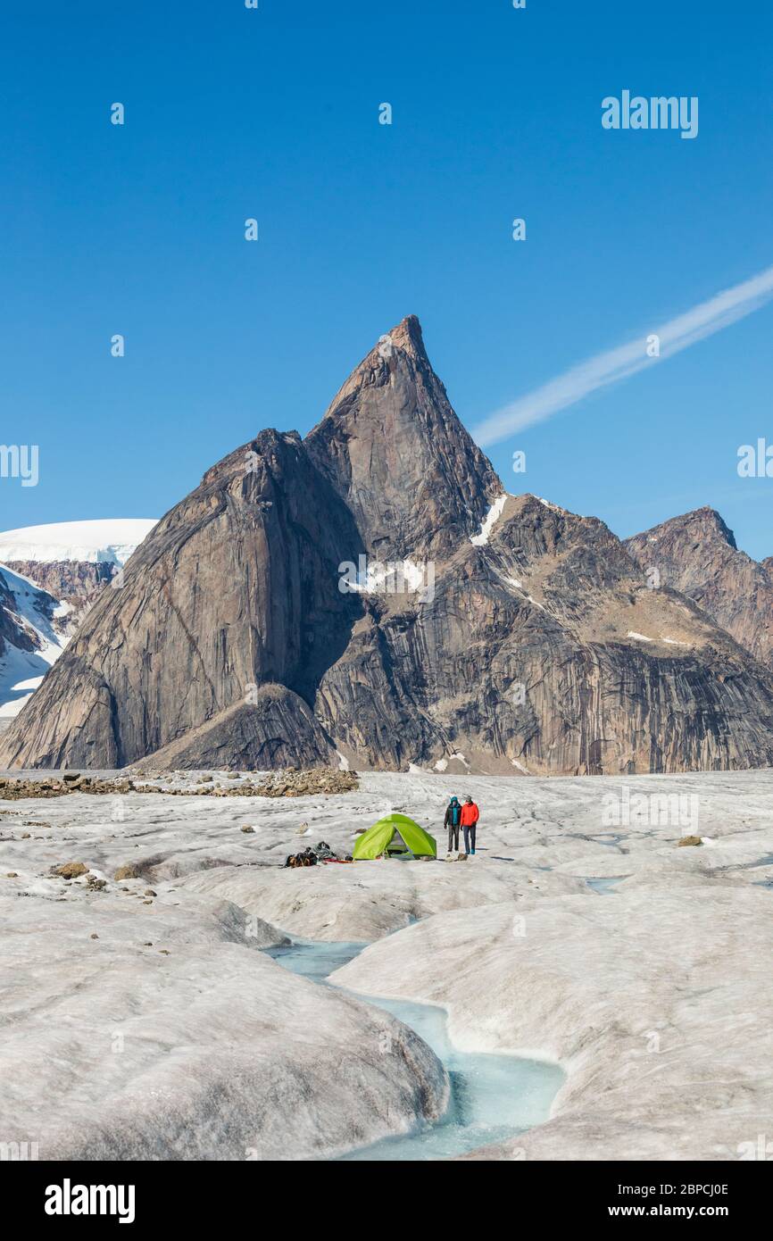Due alpinisti si trovano accanto alla tenda sul ghiacciaio sotto la cima della montagna. Foto Stock