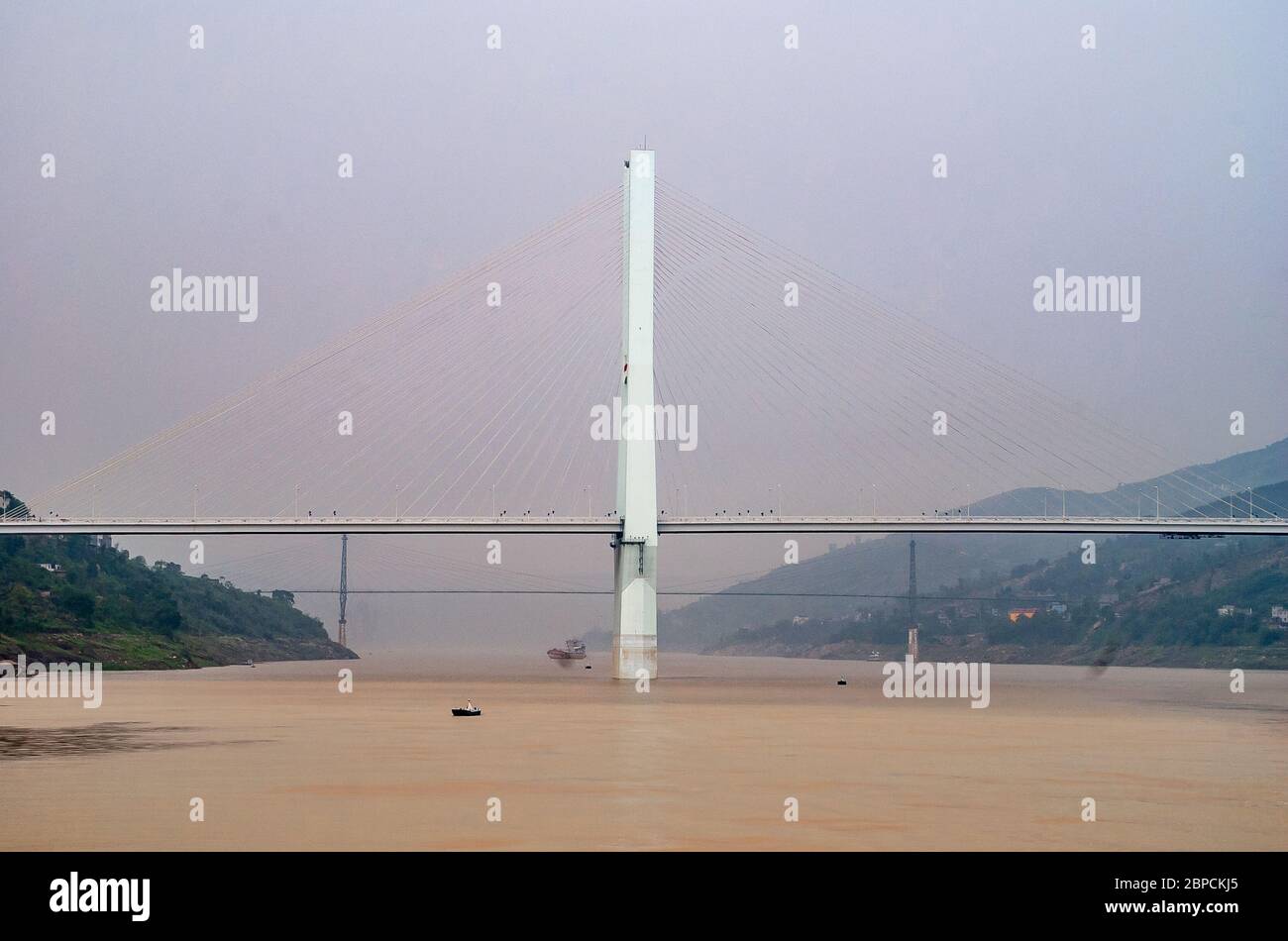 Fengdu, Chongqing, Cina - 8 maggio 2010: Fiume Yangtze. Torre di sospensione di calcestruzzo o pilone di ponte sospeso in mezzo all'acqua marrone sotto il lig Foto Stock
