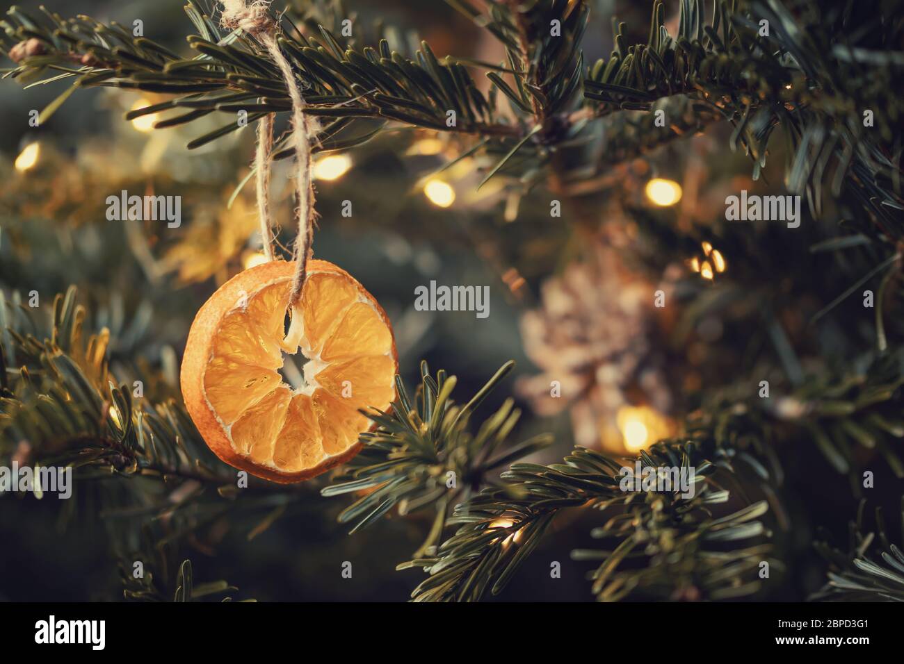 Zero rifiuti natale concetto. Albero di Natale decorato con ornamenti fatti di materiali naturali - fette di arancio secco e coni Foto Stock