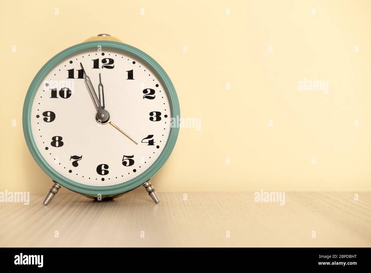 Orologio analogico antico con le mani impostate a 12:00. dalle 11:55 alle 00:00 12:00 24:00. La sveglia si trova sul tavolo Foto Stock