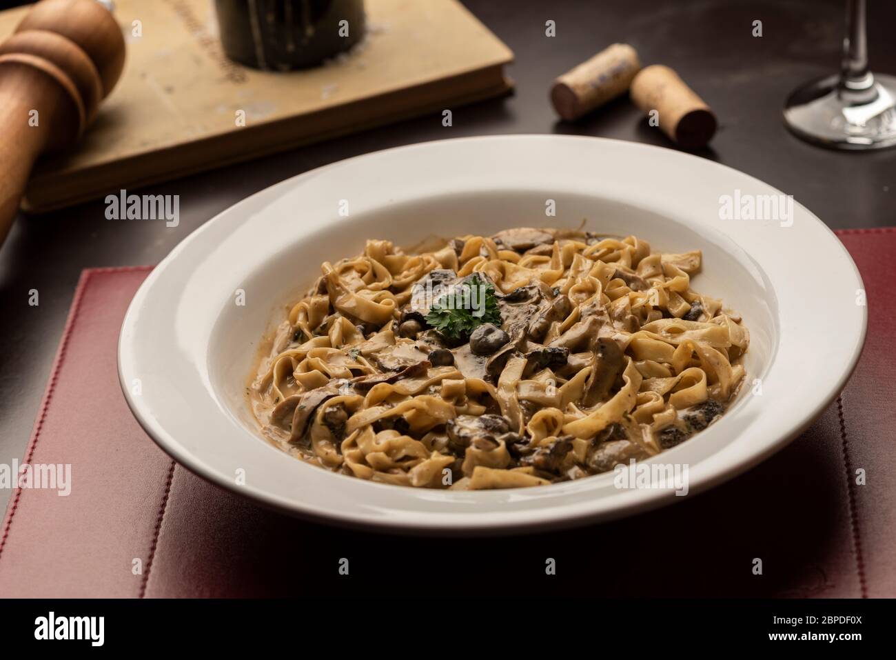 funghi funghi tagliatelle di pasta cremosa su tavola di legno vetro vino candela tappo Foto Stock