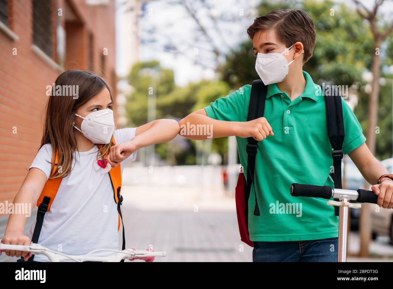 Ragazzo e ragazza con maschera di saluto per strada durante la pandemia coronavirus Foto Stock