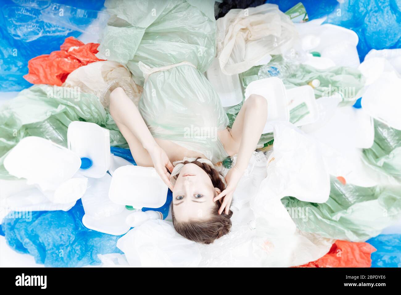 Una bella ragazza di aspetto europeo è sdraiata su una montagna di plastica. Foto Stock