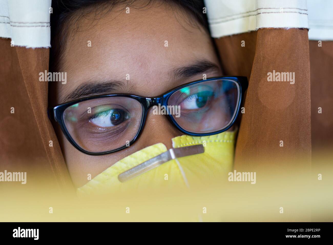 La bambina indiana rimane a casa indossando una maschera durante la quarantena domestica per la pandemia di Corona Virus COVID-19. Foto Stock