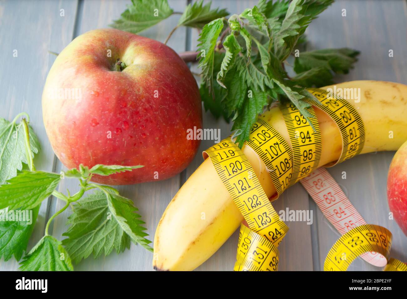 Dieta di idoneità della vitamina, mela rossa, ortica e banana con un mesure del nastro centimetrico Foto Stock