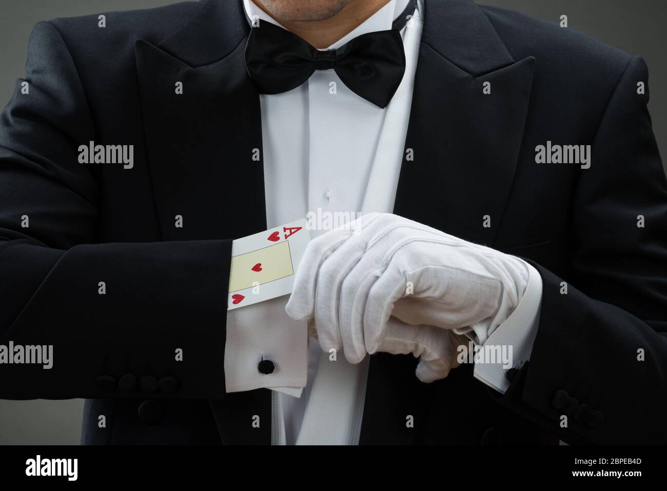 Sezione mediana del mago di eseguire la magia con carte contro uno sfondo grigio Foto Stock