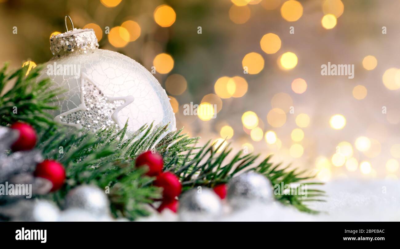Vista dettagliata del Natale e baubles rami d abete sulla neve, con defocalizzata golden lights in background Foto Stock