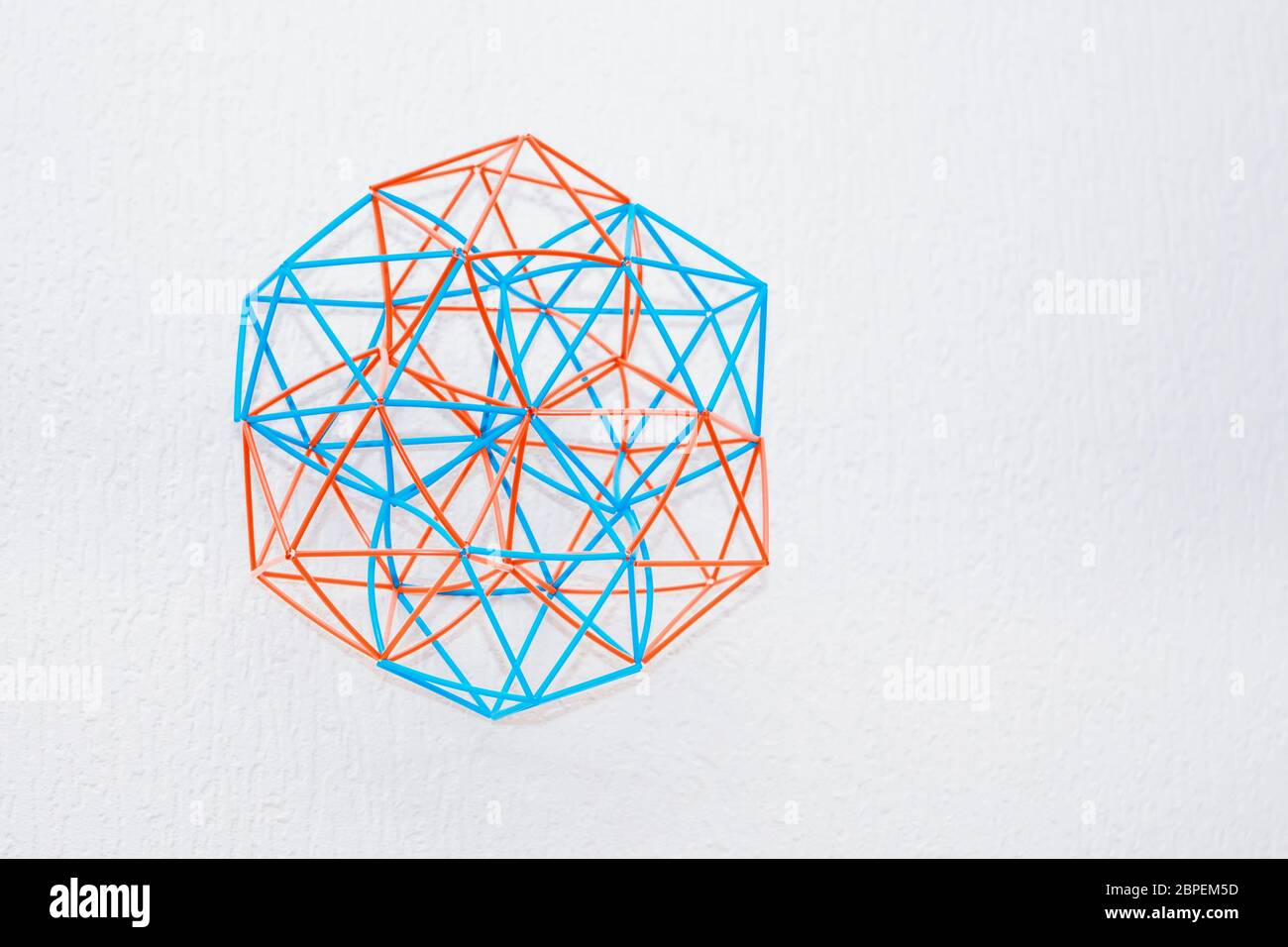 Il turchese e arancione a mano modello tridimensionale del solido geometrico su un bianco sullo sfondo a trama. Foto Stock