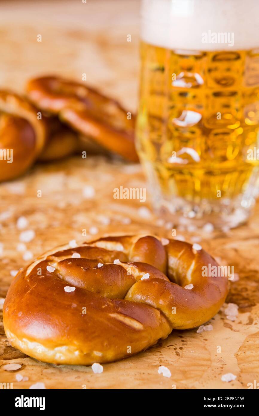 Primo piano di cottura Salato pretzel e birra chiara sulla carta oleata Foto Stock