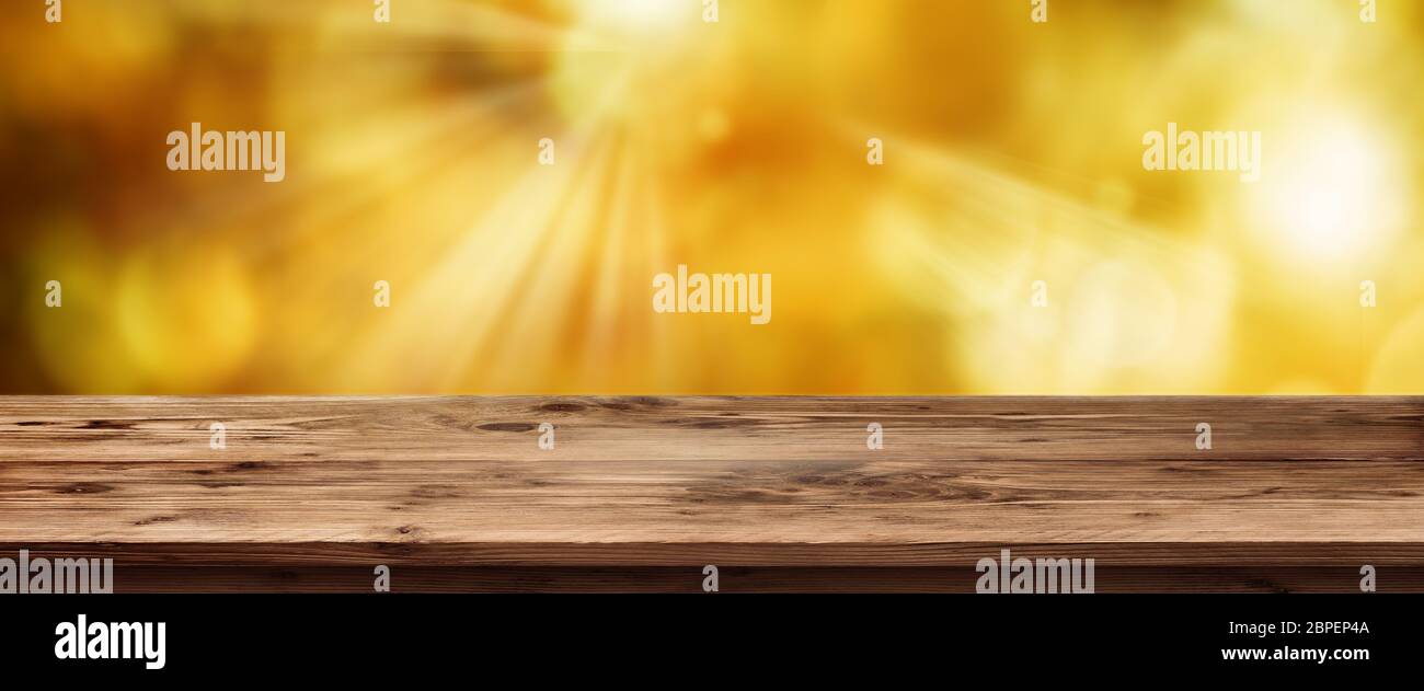 Primavera soleggiata con sfondo fuori fuoco alberi e vuota una tavola in legno rustico per un concetto Foto Stock