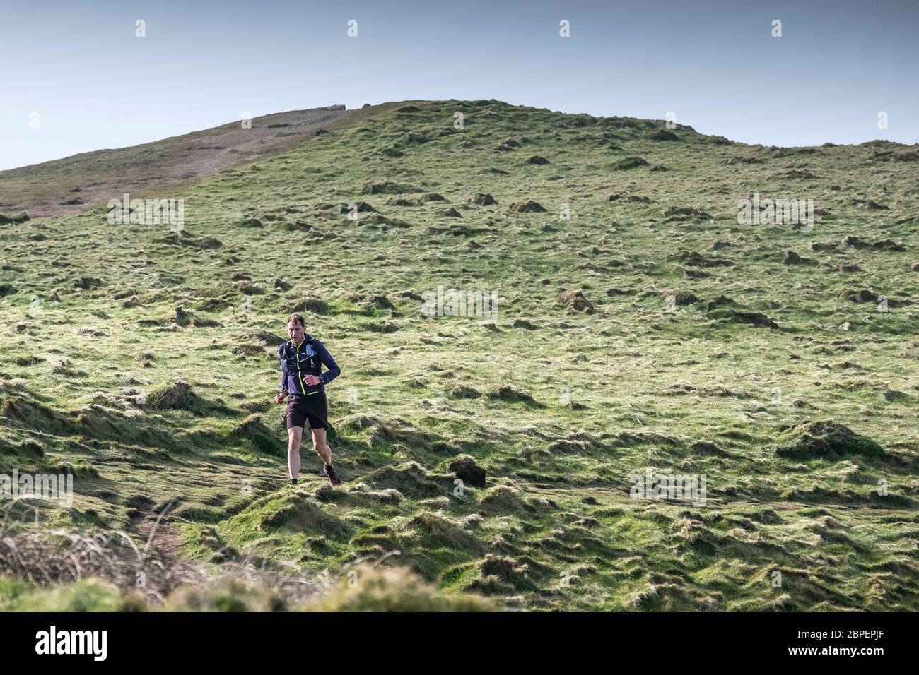 Un uomo che corre su un sentiero lungo il Penth Point East sulla costa di Newquay in Cornovaglia. Foto Stock