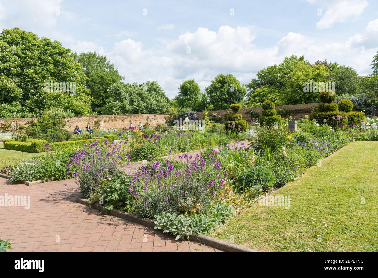 Le persone si rilassano nel giardino murato dell'Eastcote House Gardens durante una giornata soleggiata e calda in tarda primavera. Inghilterra, Regno Unito. Foto Stock