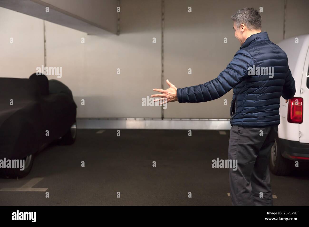 Vista posteriore di un scioccato uomo in piedi nel parcheggio dopo la sua auto è stata rubata Foto Stock
