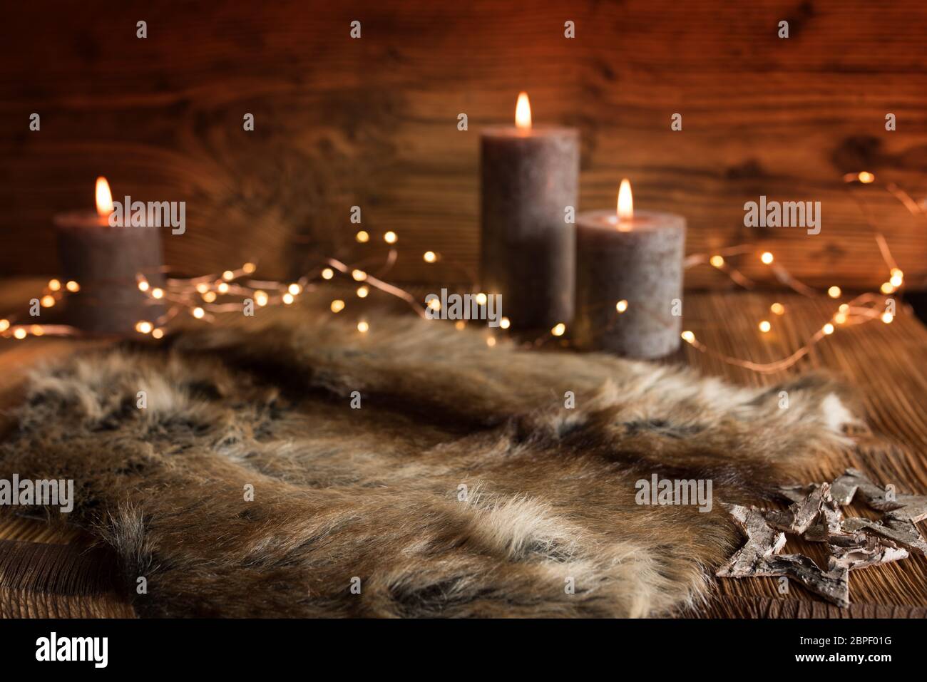 Accogliente decorazione di natale con candele e pelliccia in una serata invernale con breve profondità di campo Foto Stock