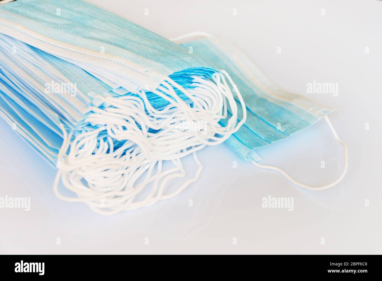 Pila di maschere chirurgiche monouso medico su sfondo bianco panoramico con spazio di copia, immagine di protezione Covid-19 Foto Stock