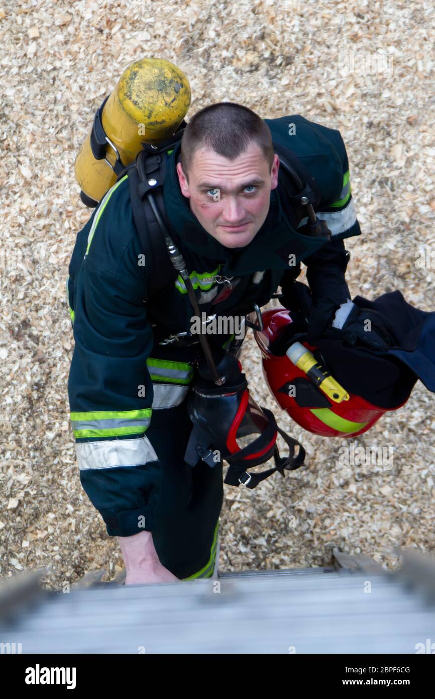 Vigili del fuoco. Un uomo in tuta da vigile del fuoco guarda in alto. Brutale vigile del fuoco. Spegnere un incendio. Foto Stock