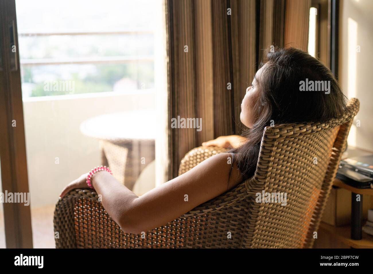 Immagine concettuale dei problemi che circondano la salute mentale.UNA donna seduta in una sedia stares fuori da una finestra aperta durante un periodo di quarantena nel COVID-19 Pandemic 2020 Foto Stock