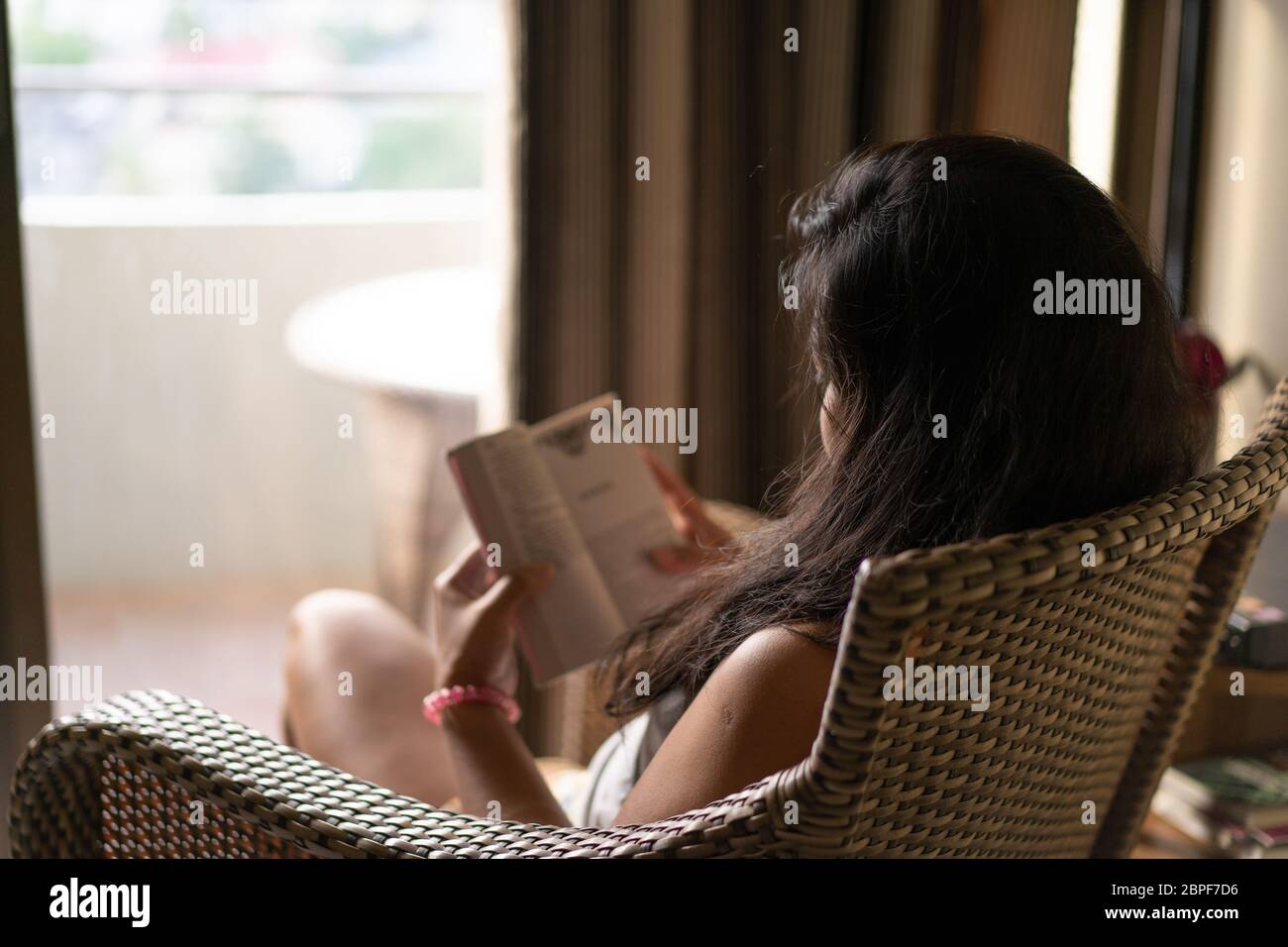 Una donna seduta in una sedia che legge un libro durante un periodo di quarantena nel COVID-19 Pandemic 2020 Foto Stock
