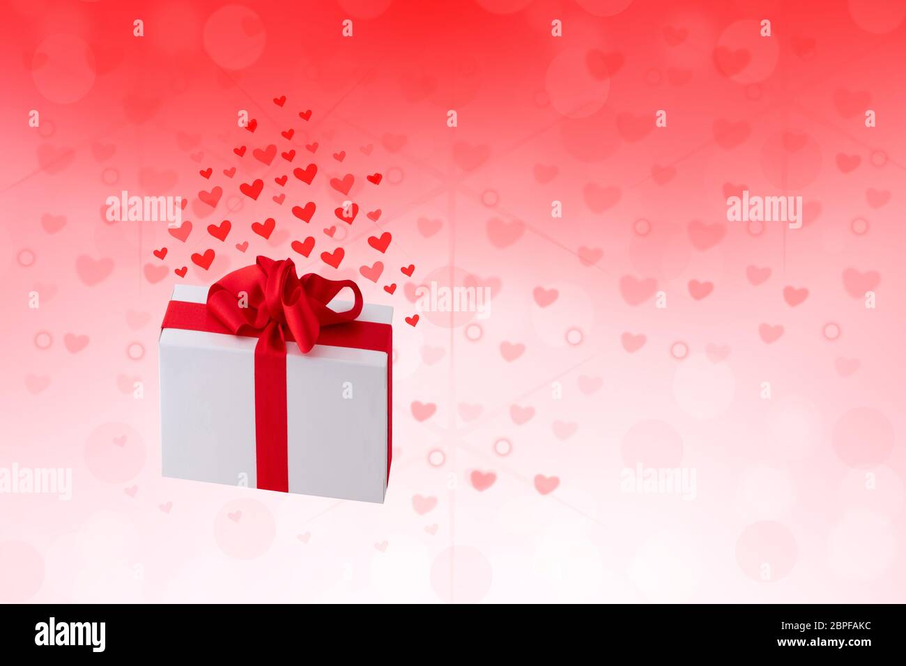 Buon San Valentino o giorno di nozze. Astratto amore romantico vacanza sfondo rosso con cuori e una scatola regalo con nastro rosso. Template con spazio per voi Foto Stock