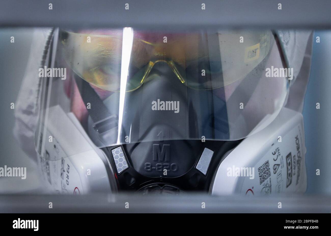 Un membro del team di custodia di PSNI Musgrave Street guarda attraverso una porta cellulare che indossa i DPI necessari per interagire con una persona sospetta detenuta da Covid-19 in un blocco di detenzione presso la stazione di Belfast. PA Media ha avuto il primo accesso esclusivo al blocco Covid-19 per assistere a come il Servizio di polizia dell'Irlanda del Nord (PSNI) si è adattato alle sfide della custodia in una pandemia. Foto Stock