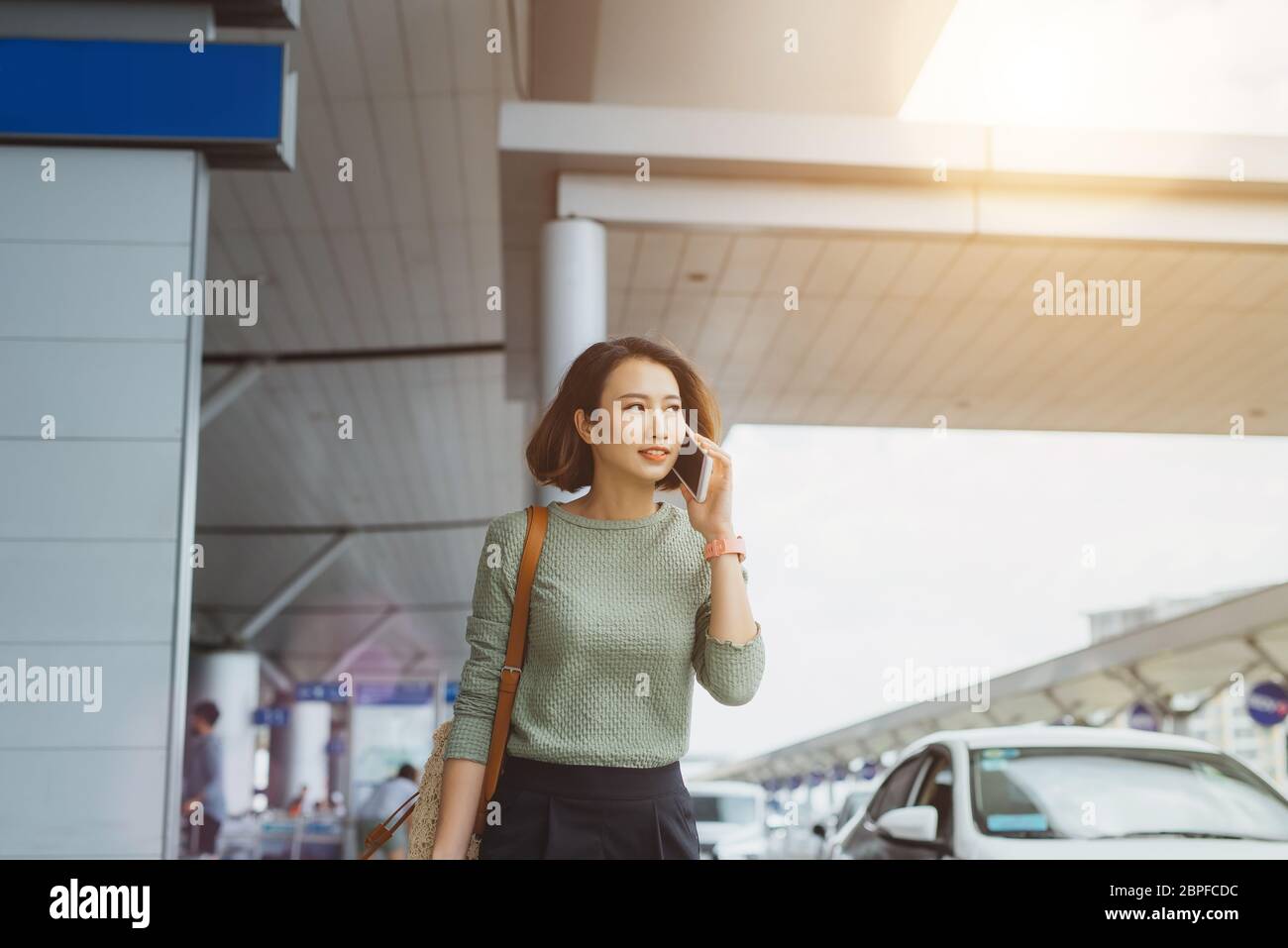 Uomo d'affari in viaggio di lavoro che parla sullo smartphone mentre cammina con i bagagli a mano nella stazione ferroviaria o con l'airpot che va al cancello d'imbarco Foto Stock