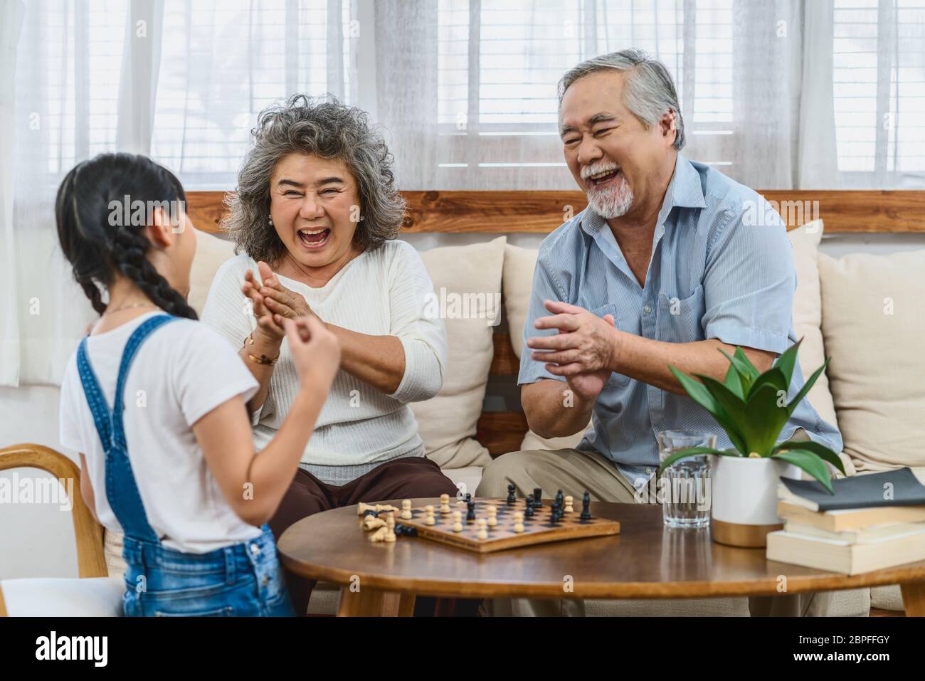Coppia asiatica nonno con nipote giocare a scacchi con felice sensazione insieme, celebrare e vincere, vita lunga e società anziana, caldo fa Foto Stock Coppia asiatica nonno con nipote giocare a scacchi con felice sensazione insieme, celebrare e vincere, vita lunga e società anziana, caldo fa Foto Stock