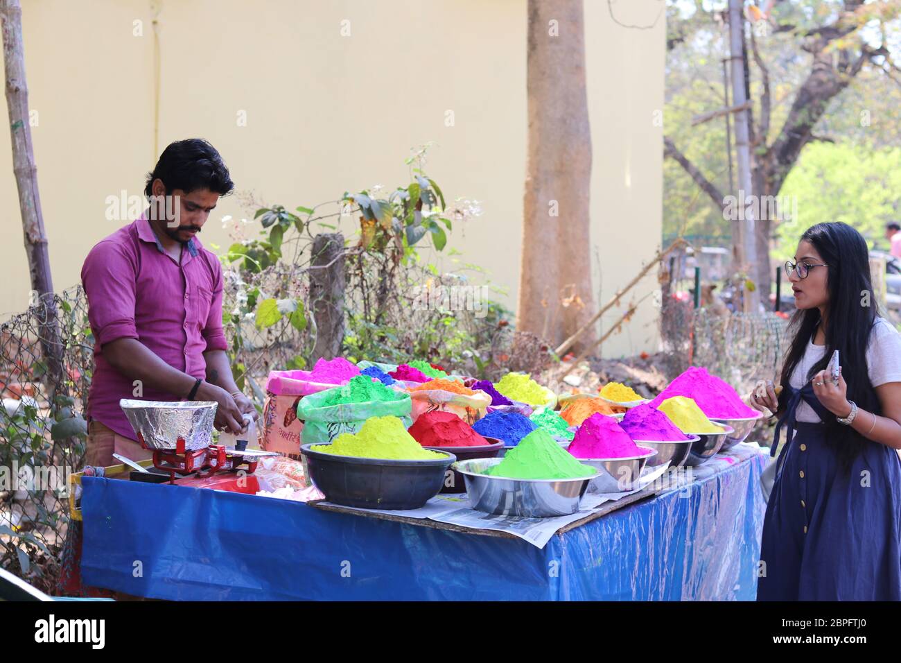 Una ragazza in Bolpur Street Market Stall acquisto polvere colori secchi in occasione Holi Festival. Holi è famoso Festival dei colori celebrati tutti indiani Foto Stock