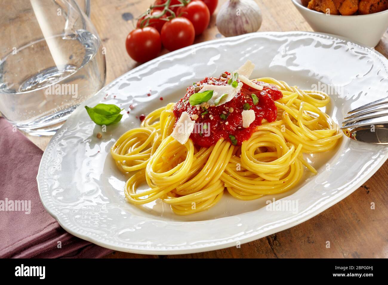 Piatto di spaghetti bolognese o bolognese con un pomodoro e basilico topping spruzzata wth parmigiano reggiano in una vista inclinata su di un tavolo di legno Foto Stock