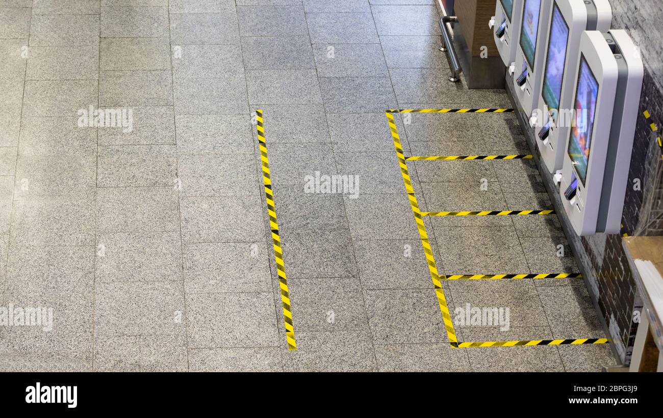 Marcatura sicura delle linee gialle sul piano - misure per la distanza sociale vicino ai banchi di cassa self-service in un fast food durante il coronavi Foto Stock