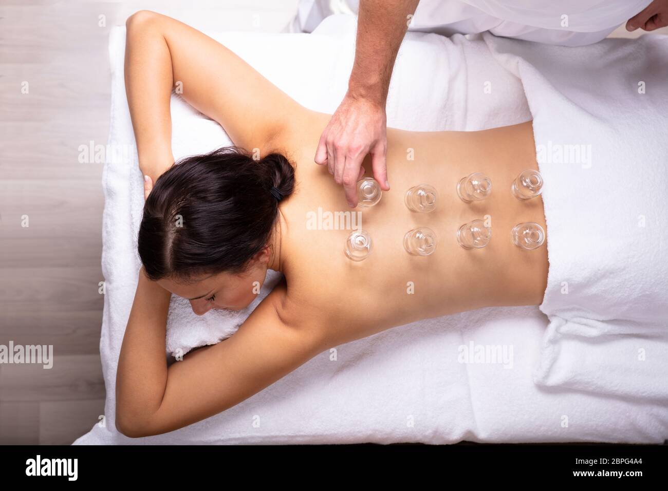 Rilassata giovane donna ricevere trattamento Cupping sulla sua schiena In Spa Foto Stock