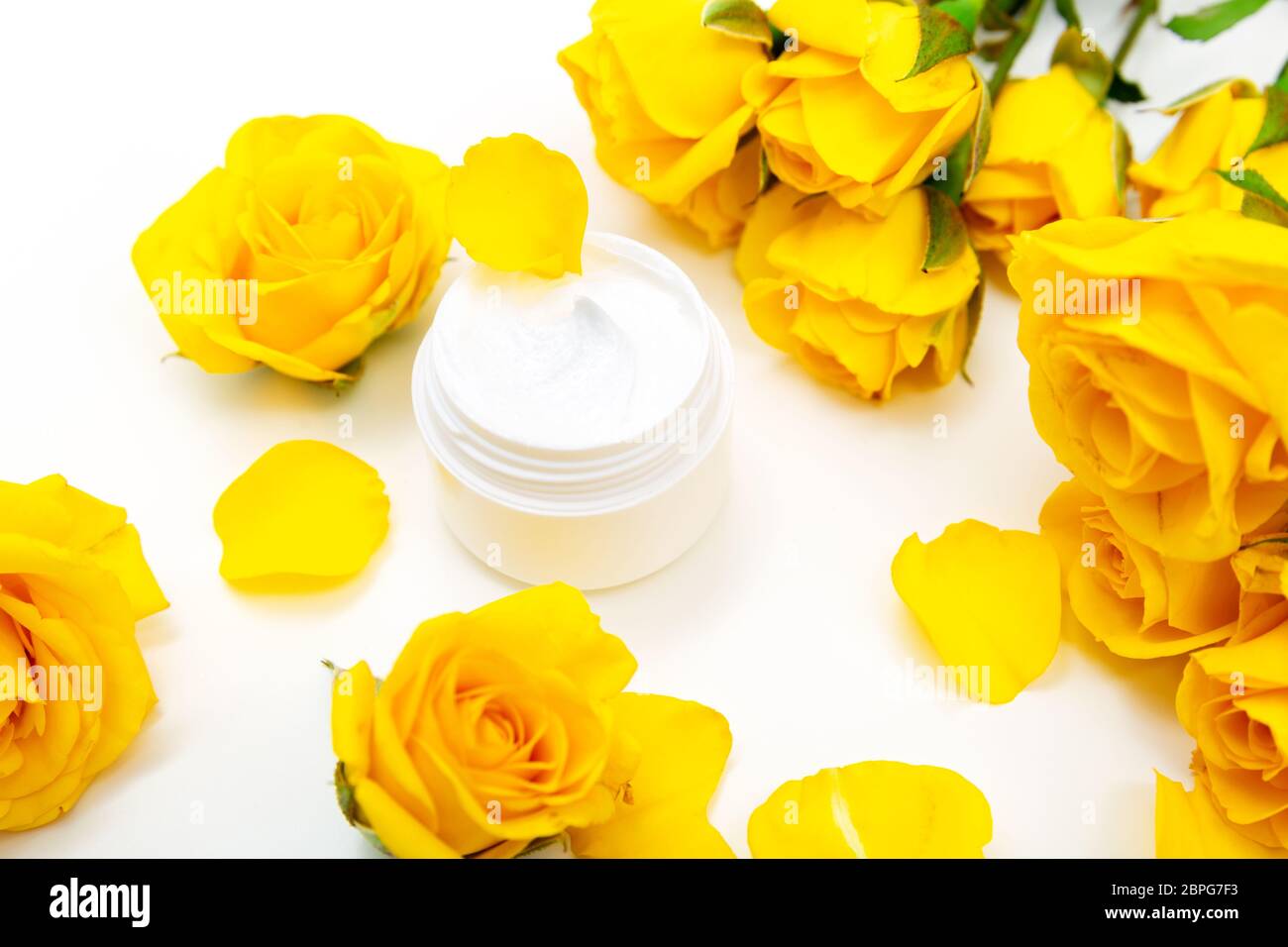 Botanico aromatico cosmetici. Dermocosmesi home trattamenti spa con petali gialli, bocciolo di rosa, naturale crema per il viso Foto Stock