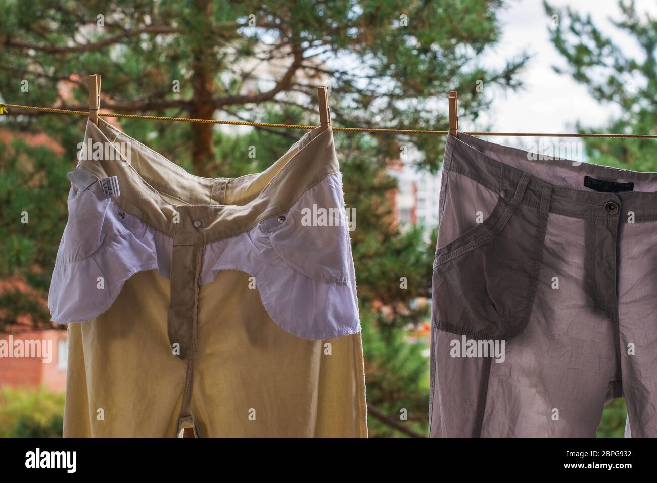I pantaloni sono asciugati dopo il lavaggio su una corda in una giornata di sole. Sfondo sfocato il concetto di lavaggio e pulizia. Colori caldi Foto Stock