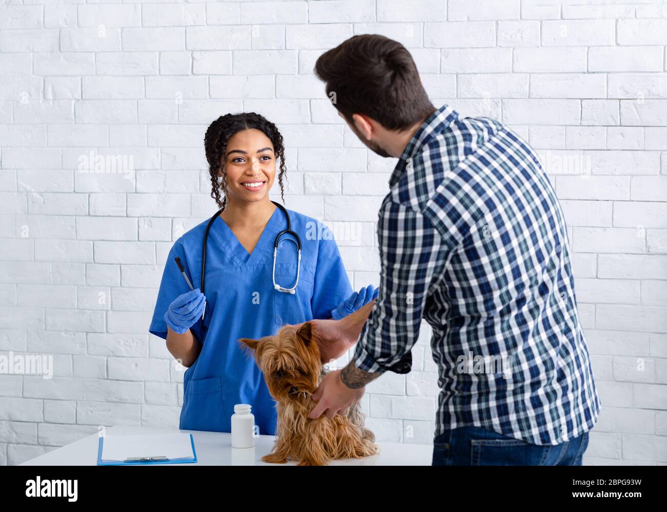 Veterinario giovane che parla con il proprietario del cane su meds prescritto in clinica animale Foto Stock