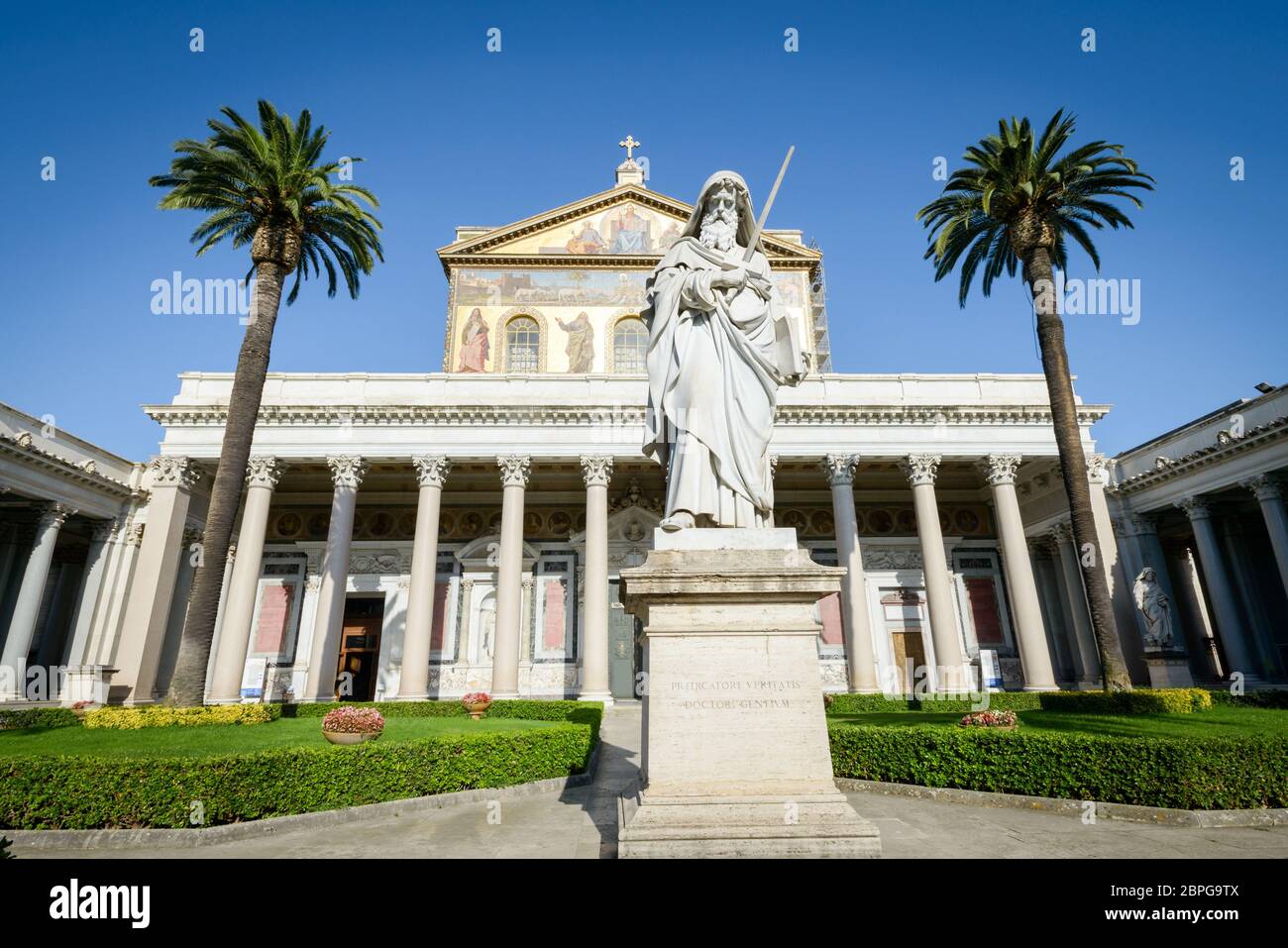 Bellissimo chiostro di San Paolo (Paolo) in Italia, Roma, statua chiesa e palme in background Foto Stock