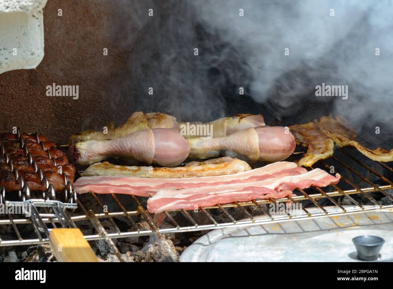 Grigliare sul barbecue salsicce e pancetta e pollo Foto Stock