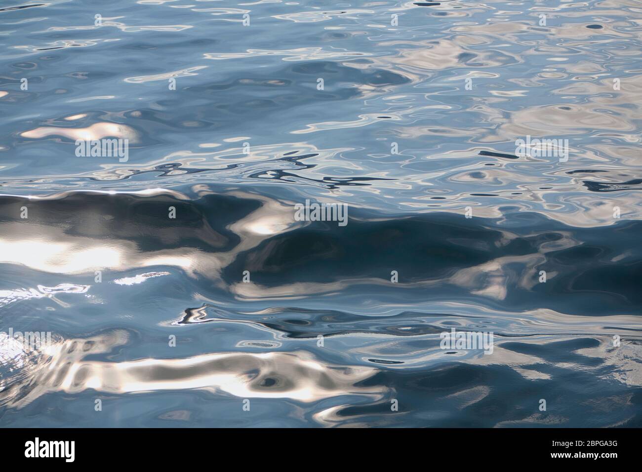 Motivi astratti e riflessi luminosi sulla superficie del mare con piccole onde Foto Stock