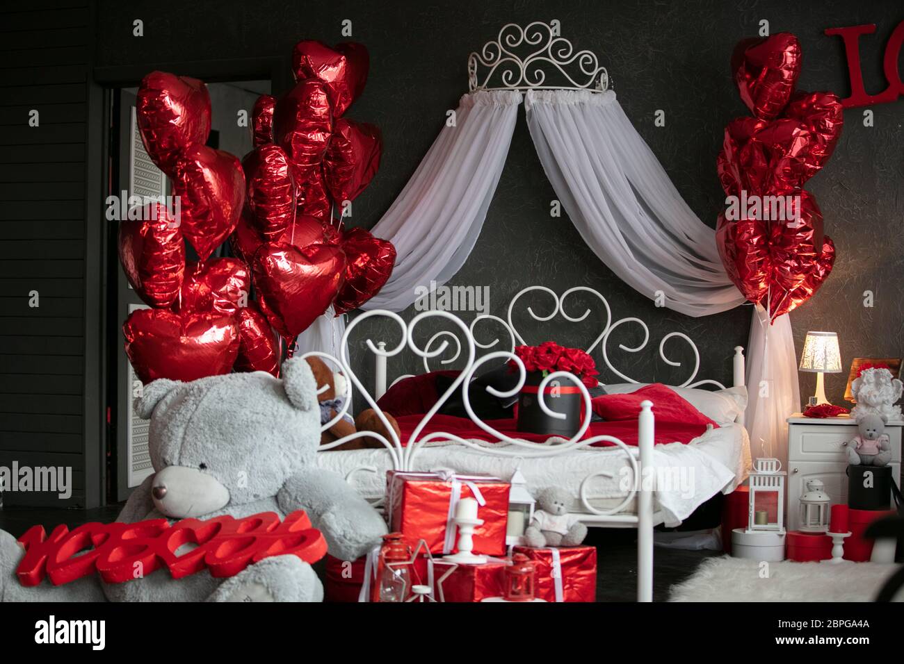 San Valentino all'interno. Camera da letto scura con letto bianco decorata  con palloncini rossi. Camera romantica interna. Camera per la notte di nozze  Foto stock - Alamy