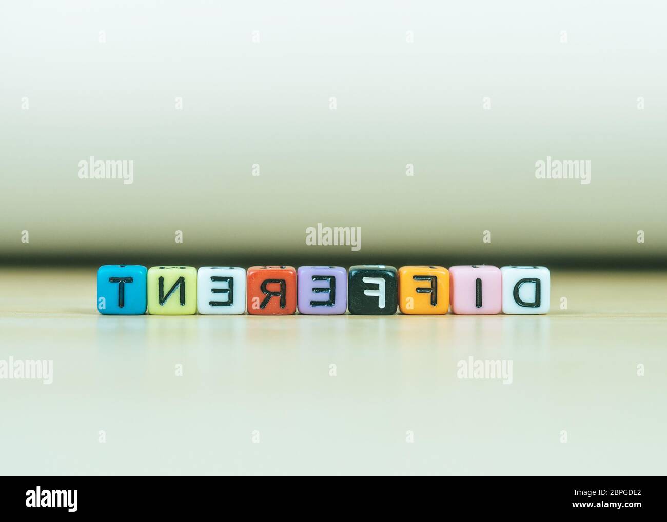 Parole DIVERSE scritte in cubo su pavimento di legno su sfondo bianco, blocchi di lettere si dispone in parole DIVERSE, per aggiungere testo o altre immagini o d Foto Stock