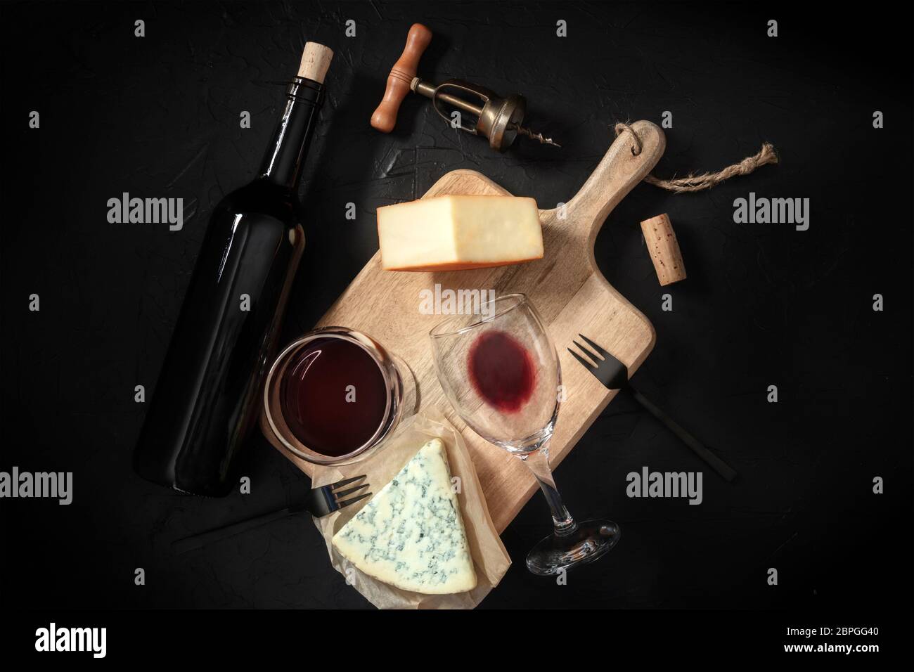 Degustazione di vino e formaggi, girato dall'alto su sfondo nero, con cavatappi vintage e una bottiglia Foto Stock
